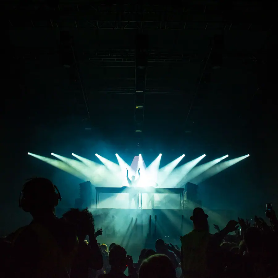 Crowd facing a stage with beams of light