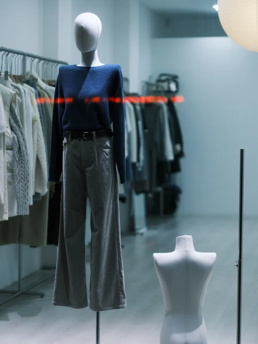 Mannequin in a boutique window beside clothing racks