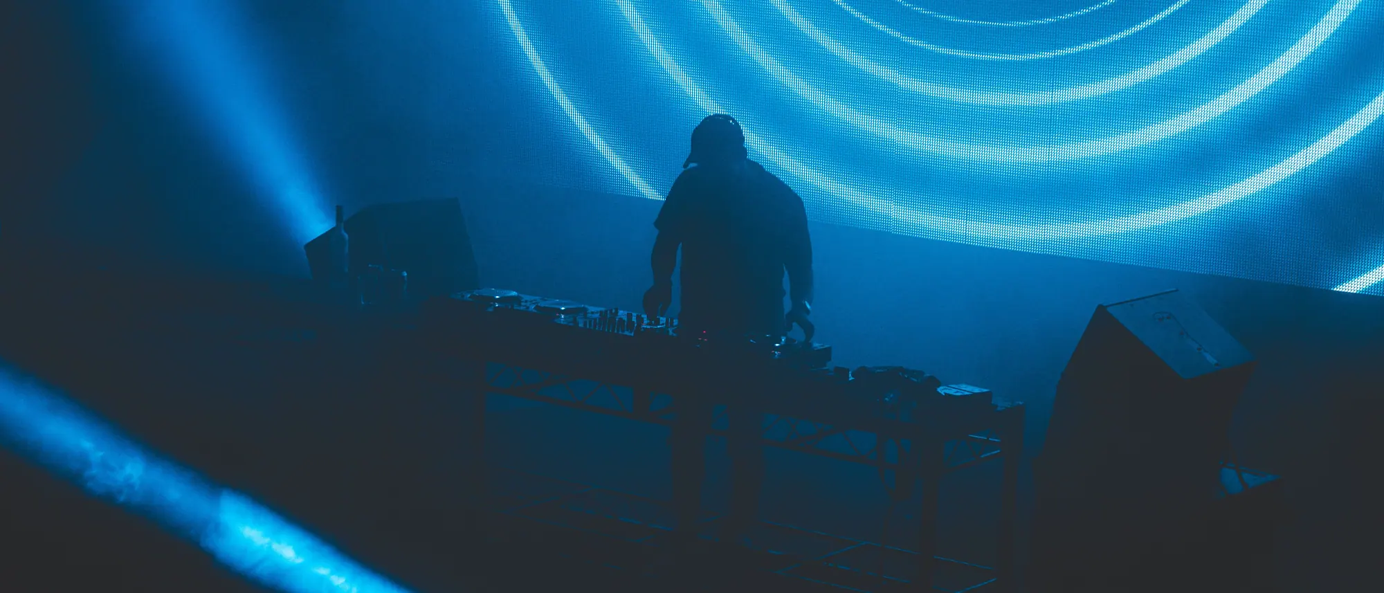 DJ silhouetted against glowing blue neon rings on a stage
