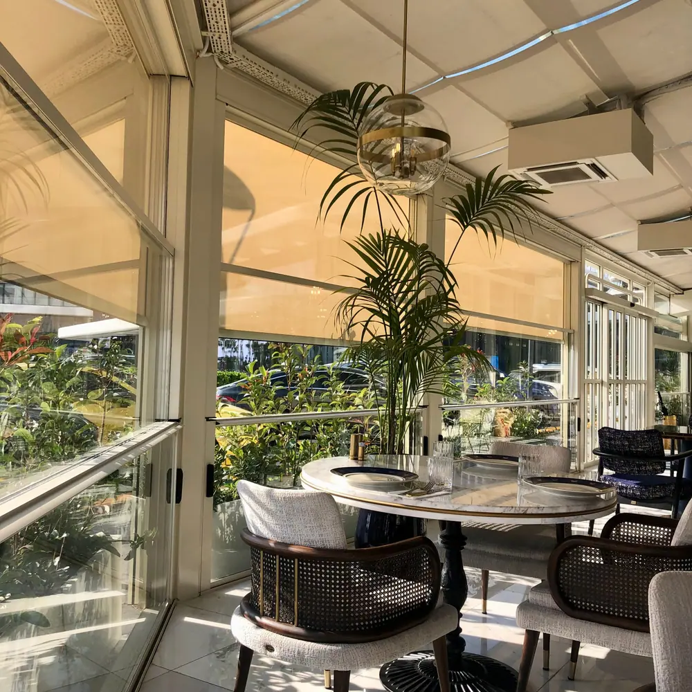 Sunlit café terrace with round tables and palm plants