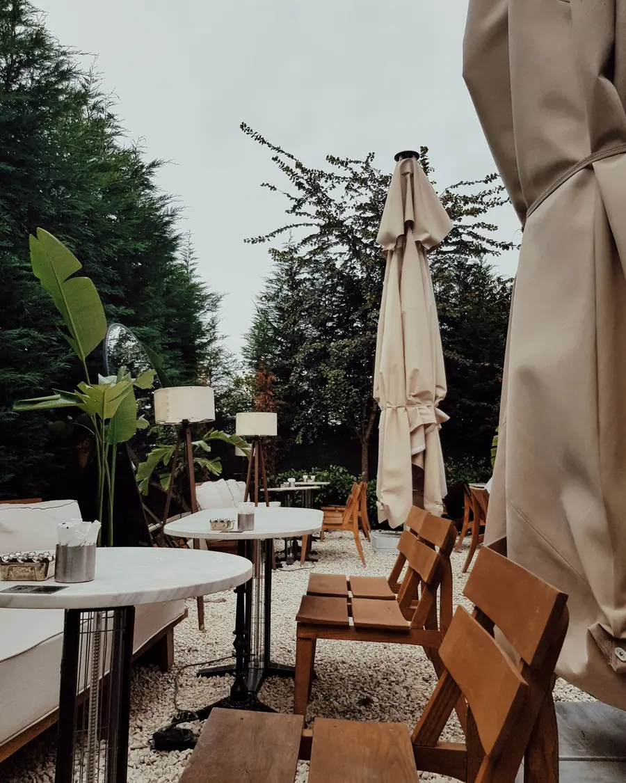 Outdoor café terrace with wooden chairs, round tables and umbrellas